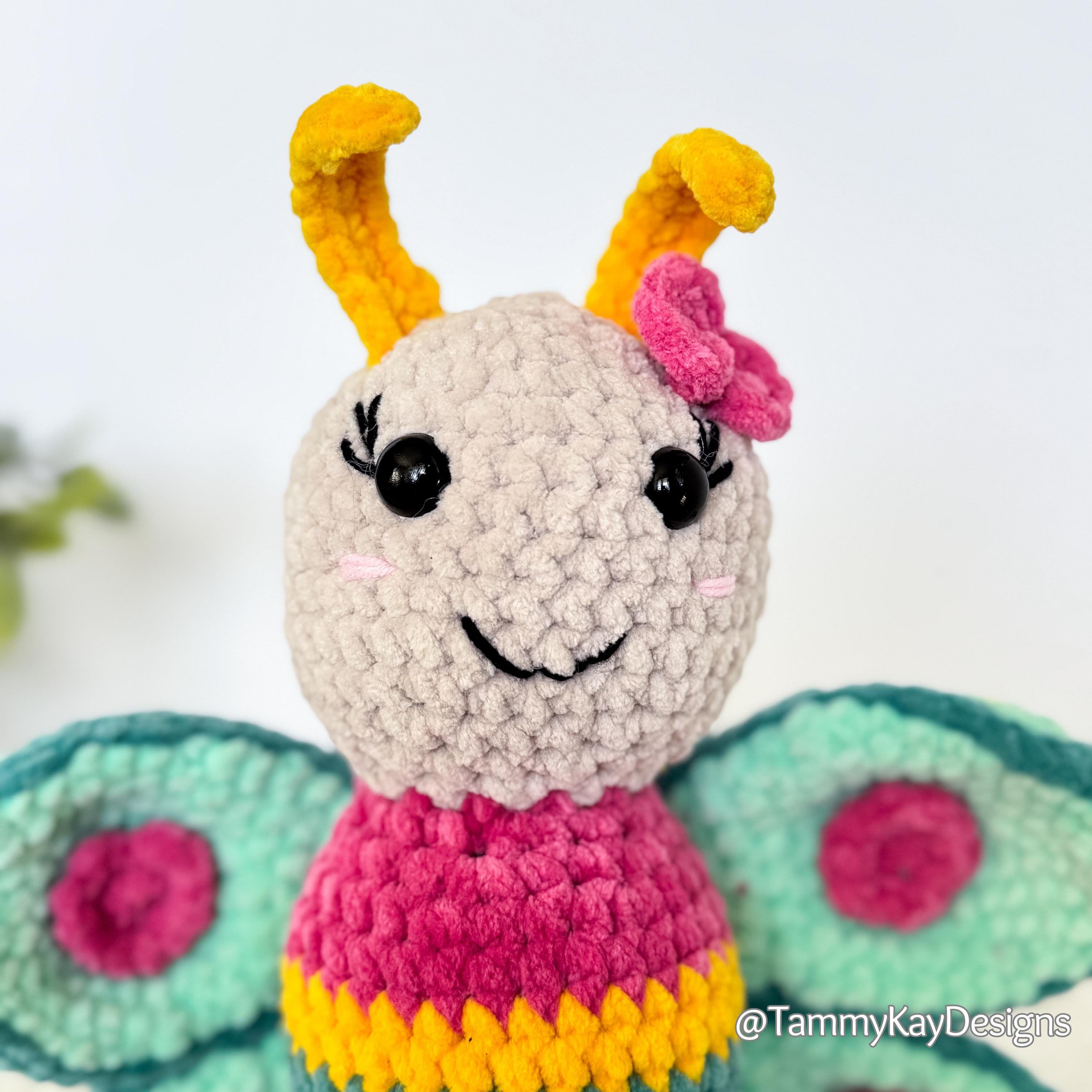 Crocheted insect toy with yellow antennae and pink body on a white background