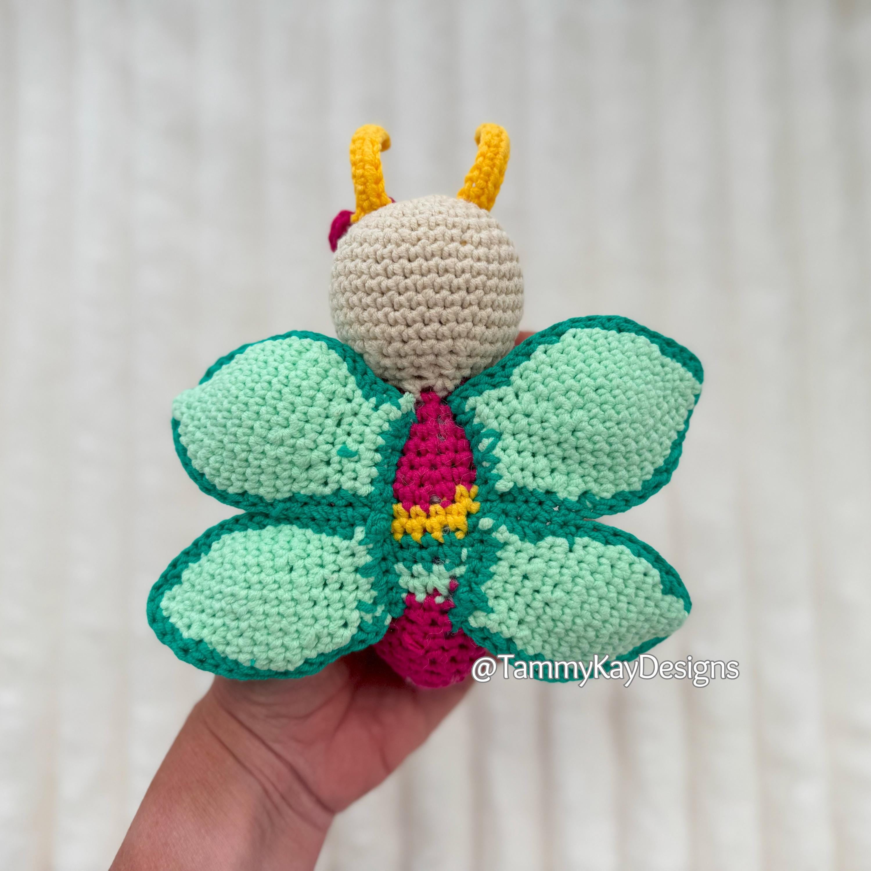 Crocheted butterfly toy held in a hand with a white background