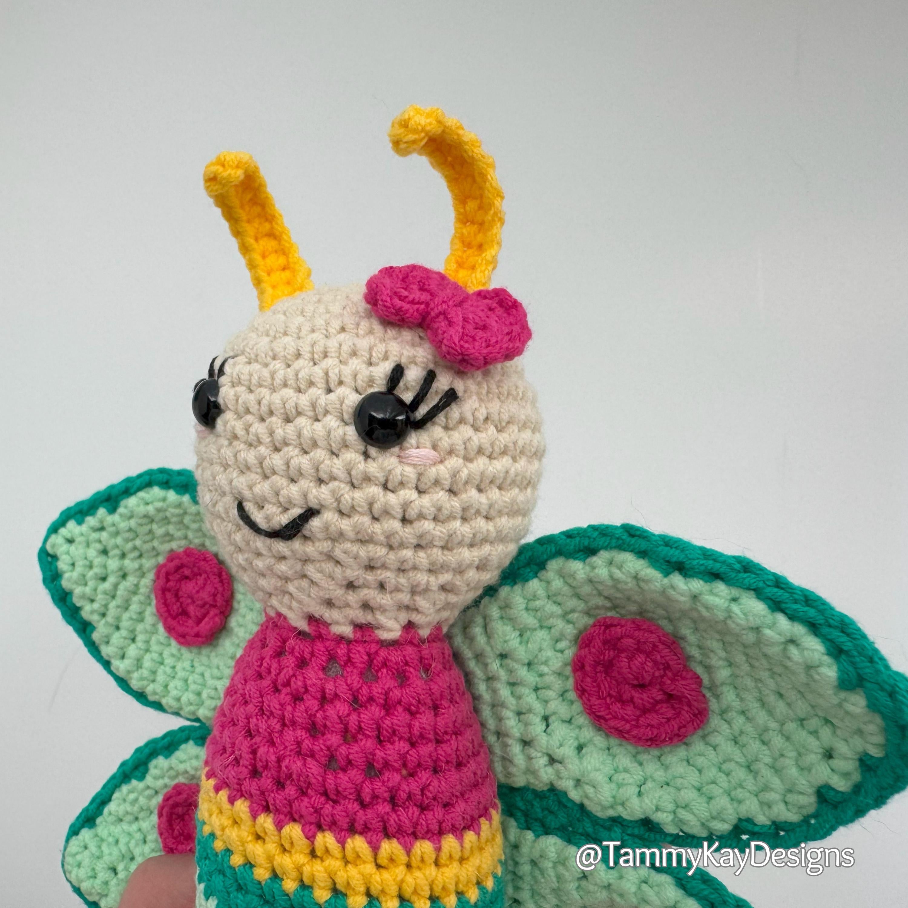 Crocheted butterfly toy with a pink bow on a white background, featuring the brand 'Tammy Kay Designs'.