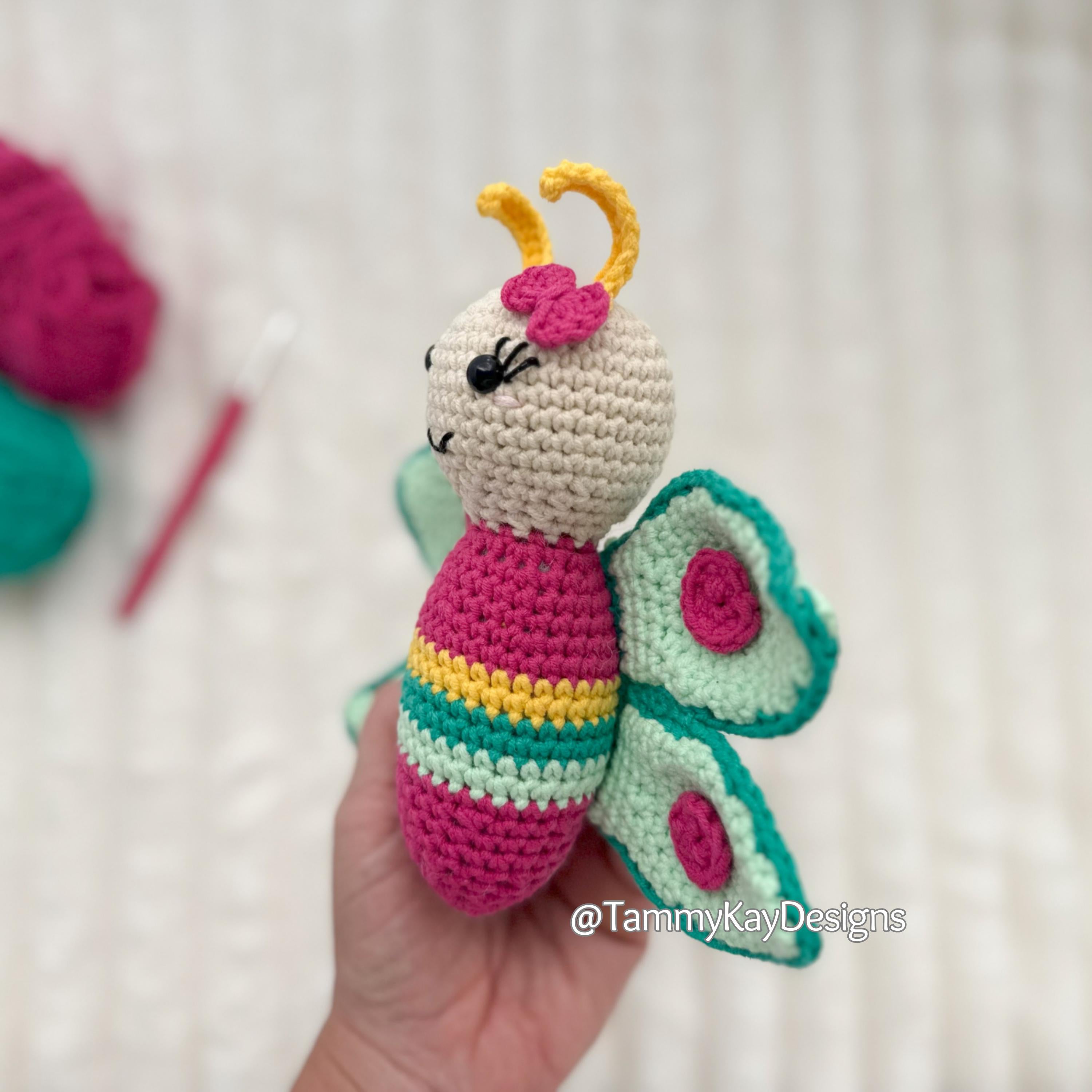 Crocheted butterfly toy held in a hand with a blurred background