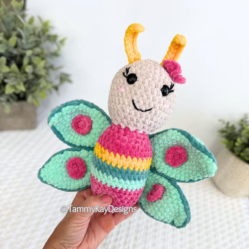 Crocheted butterfly toy held by a hand with a blurred background