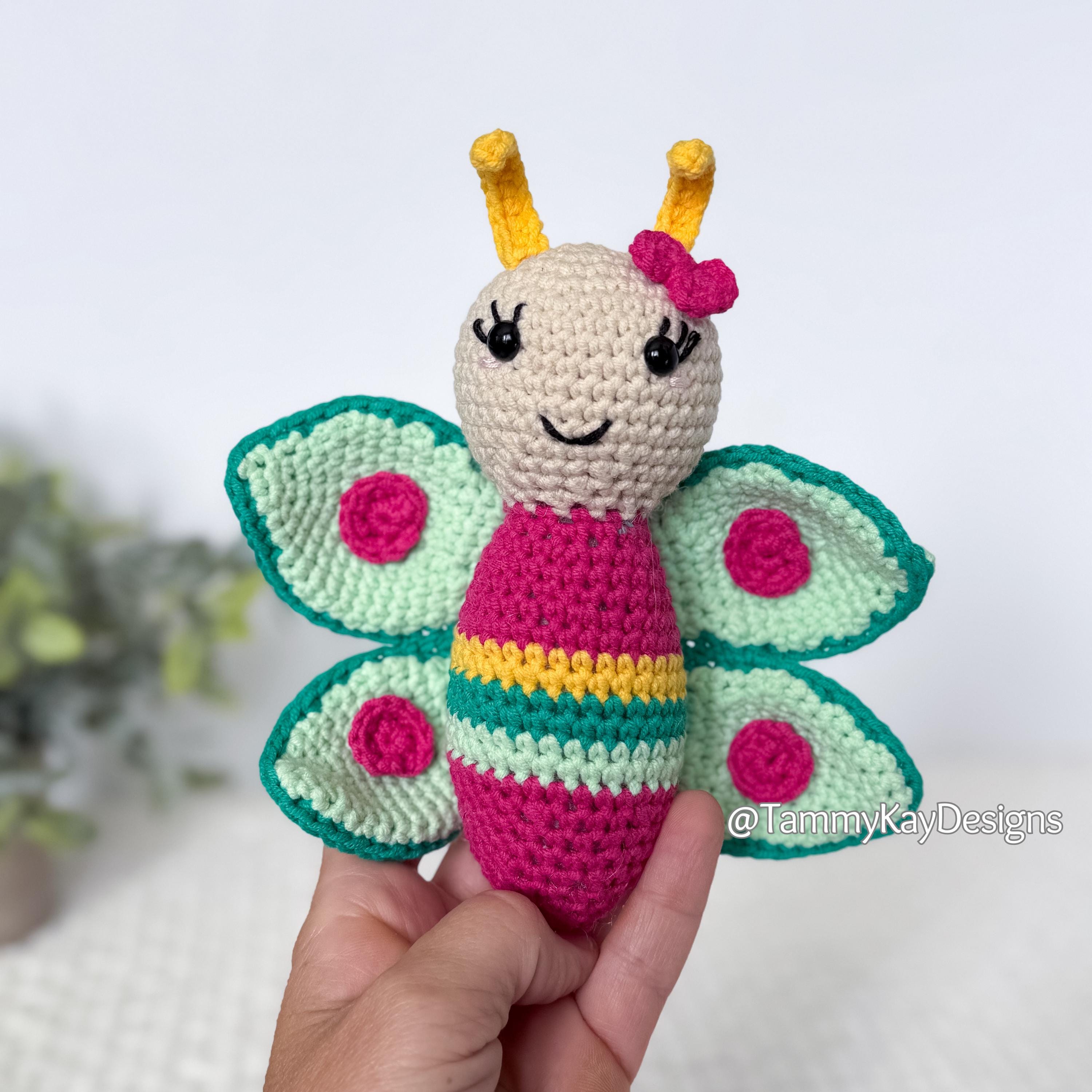 Handmade crochet butterfly toy held by a hand with a blurred background
