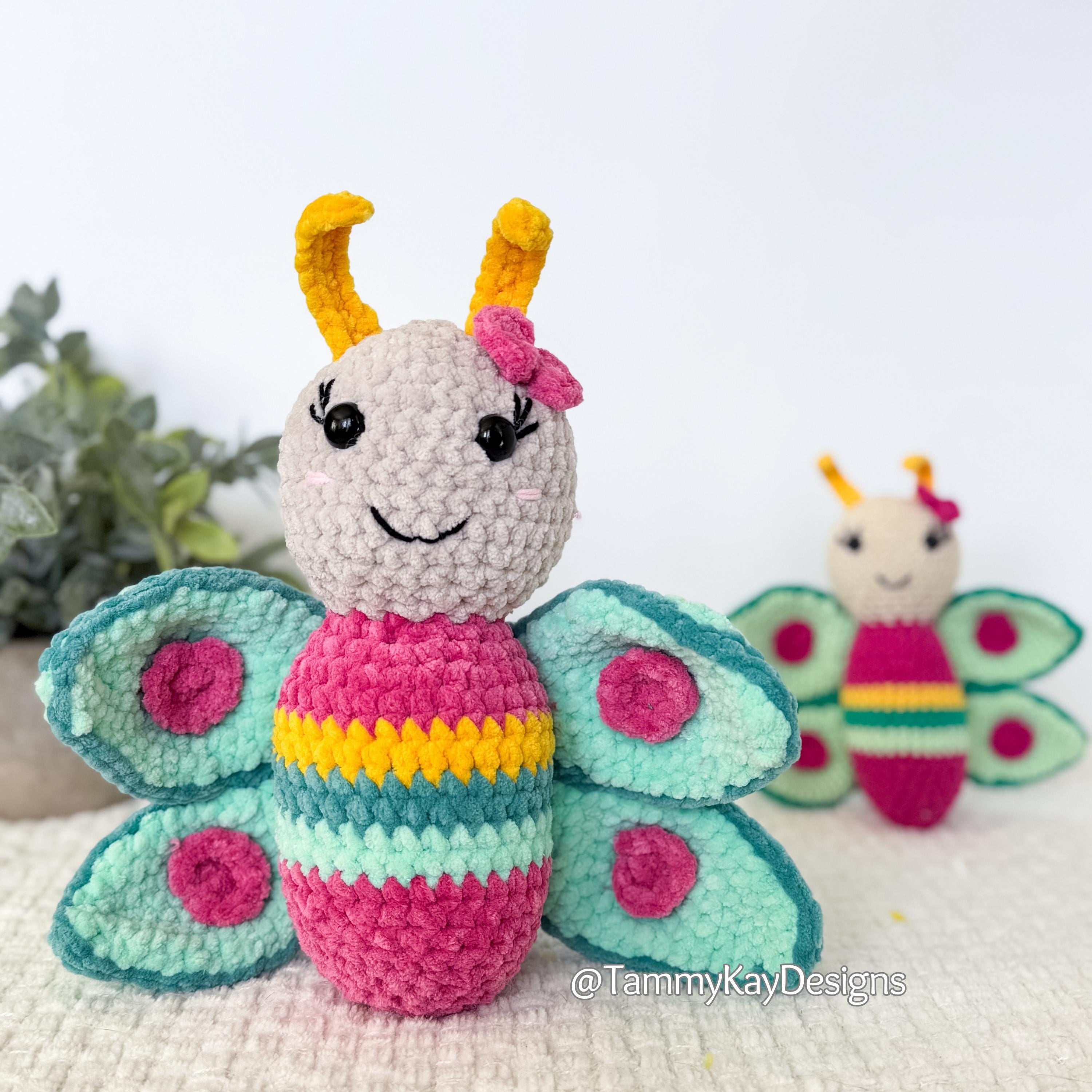 Crocheted butterfly toy with pink body and blue wings on a white background
