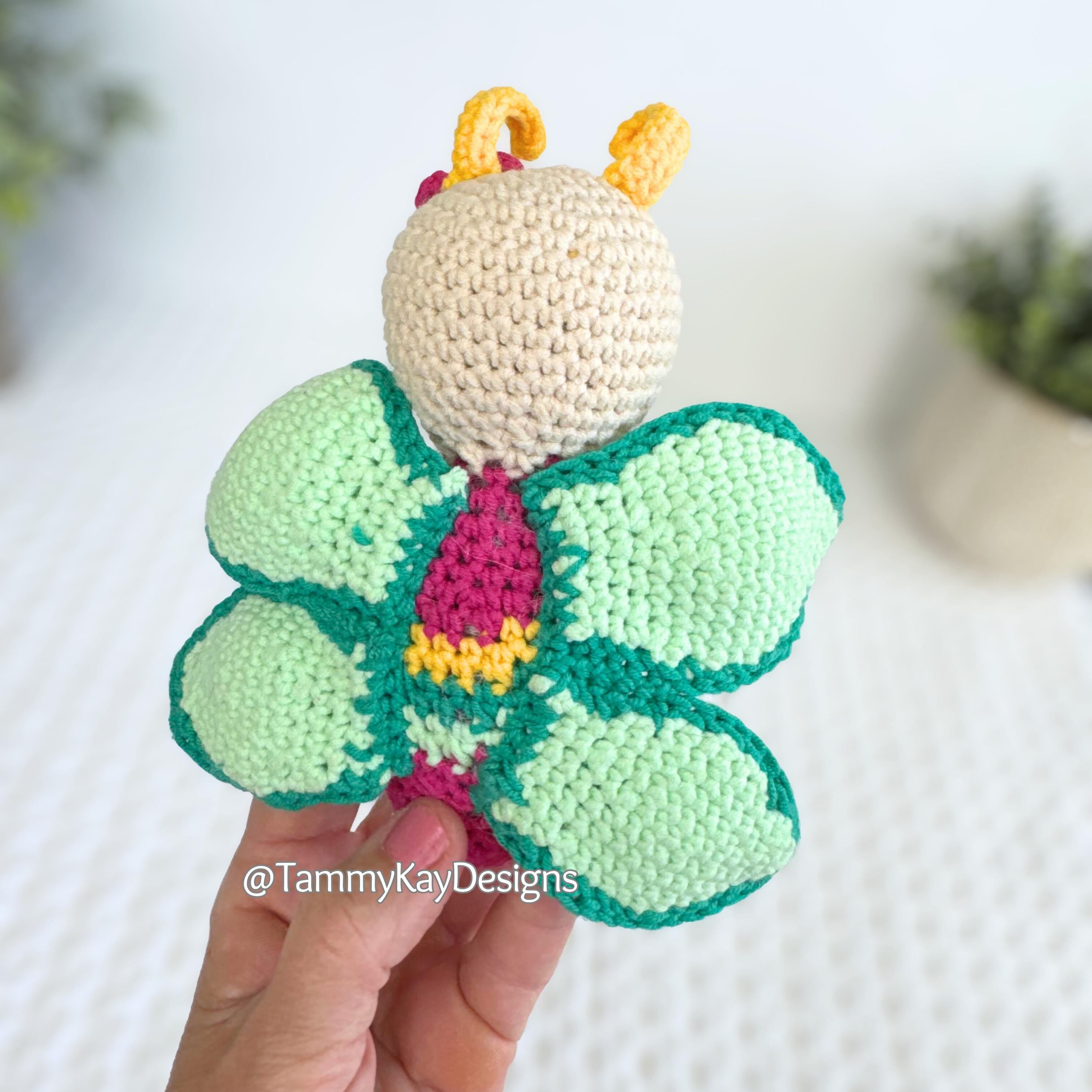 Handmade crochet butterfly toy held by a hand with a light background