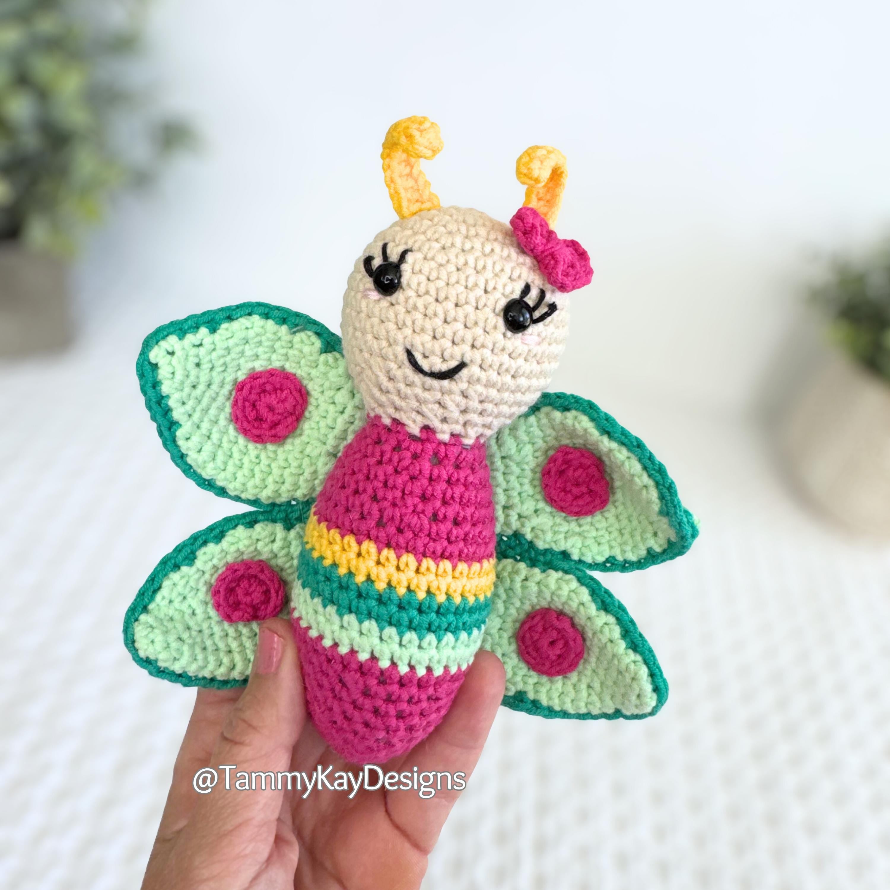 Crocheted butterfly toy held by a hand with a blurred background