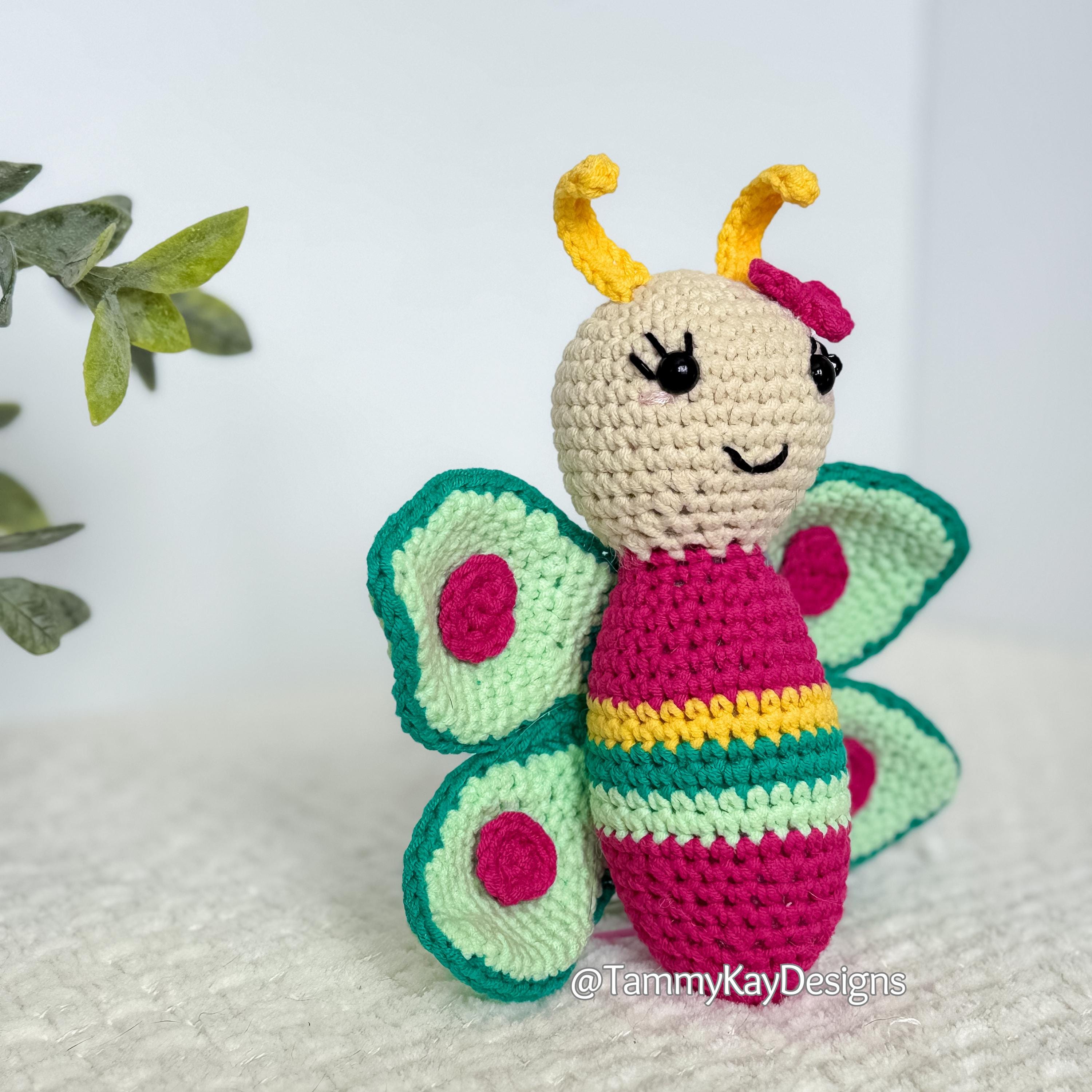 Crocheted butterfly toy with a smiling face on a white background