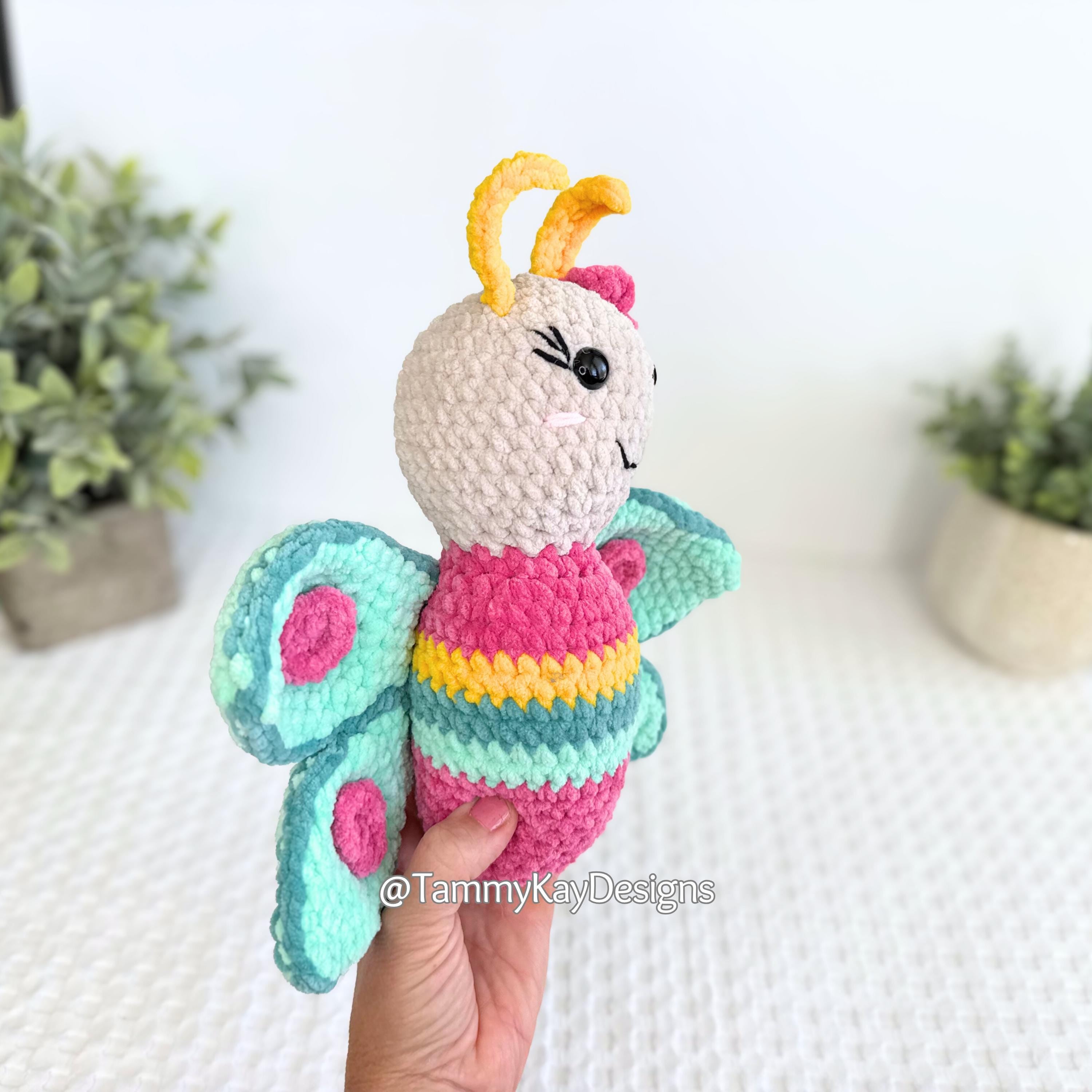 Colorful crochet butterfly toy held by a hand with a blurred background